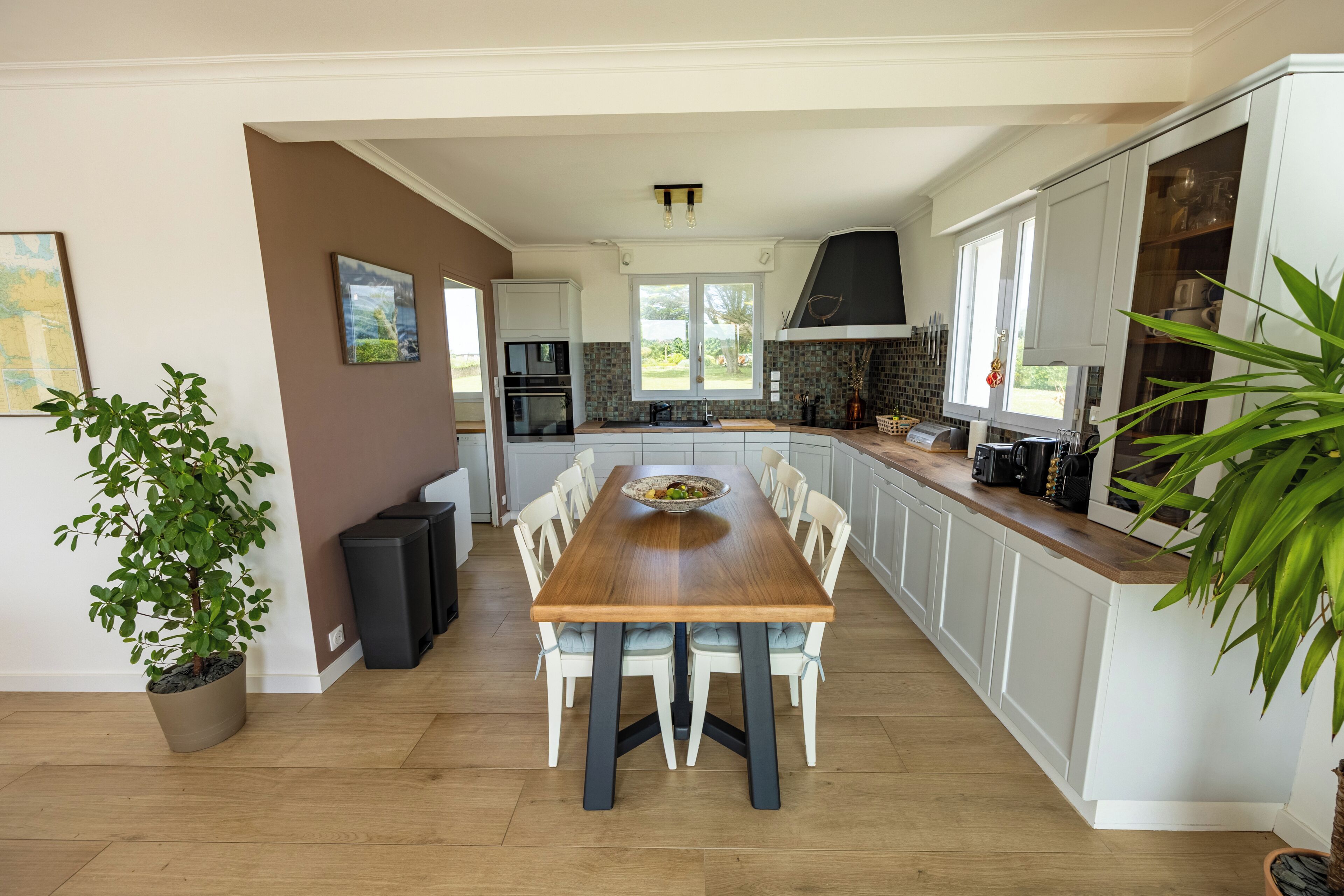 A modern kitchen with a central island, white cabinetry, and a large window.