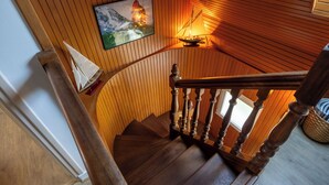 Eine Holztreppe mit einem Schiffmodell und einem gerahmten Bild an der Wand.