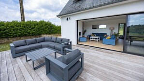 Ein moderner Außenbereich mit einer Eckcouch, einem Couchtisch und einem Esstisch.