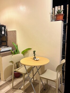 A small round table with two chairs, a potted plant, and a small table lamp. - Private Tiny Home Studio in General Luna Fast WiFi (Caraga)