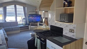 Ett kompakt bostadsutrymme med ett litet kök, en tv och en soffa.