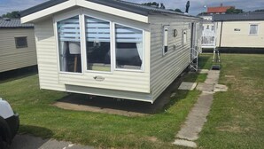 Ett hus på hjul med en veranda framtill, ett garage och ett litet förråd som sitter ihop med huset.