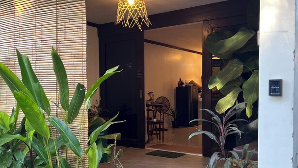 Een modern interieur met een houten bankje, potplanten en een hanglamp.