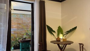 Een kamer met een eettafel, twee stoelen, een potplant en uitzicht door een glazen deur.