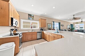 A modern kitchen with wooden cabinets, a built-in oven, and a dishwasher. - Krusty Krab | Sleeps 10 |  Bay Views Pet-Friendly (Gulf Shores)