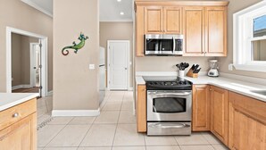 A modern kitchen with wooden cabinets, a stainless steel stove, a microwave, and a blender on the countertop. - Krusty Krab | Sleeps 10 |  Bay Views Pet-Friendly (Gulf Shores)