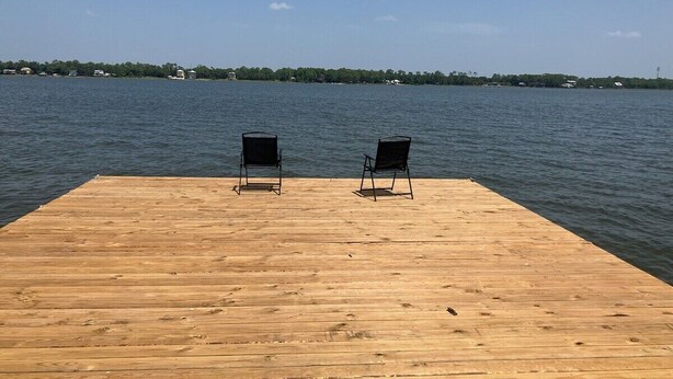 A wooden dock with two chairs facing a calm lake. - Krusty Krab | Sleeps 10 |  Bay Views Pet-Friendly (Gulf Shores)