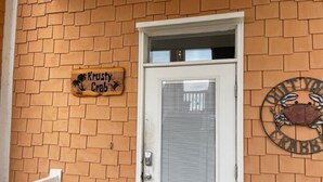 A brick building with a white door, a sign reading 'Krusty Crab,' and a metal sign with a crab design. - Krusty Krab | Sleeps 10 |  Bay Views Pet-Friendly (Gulf Shores)