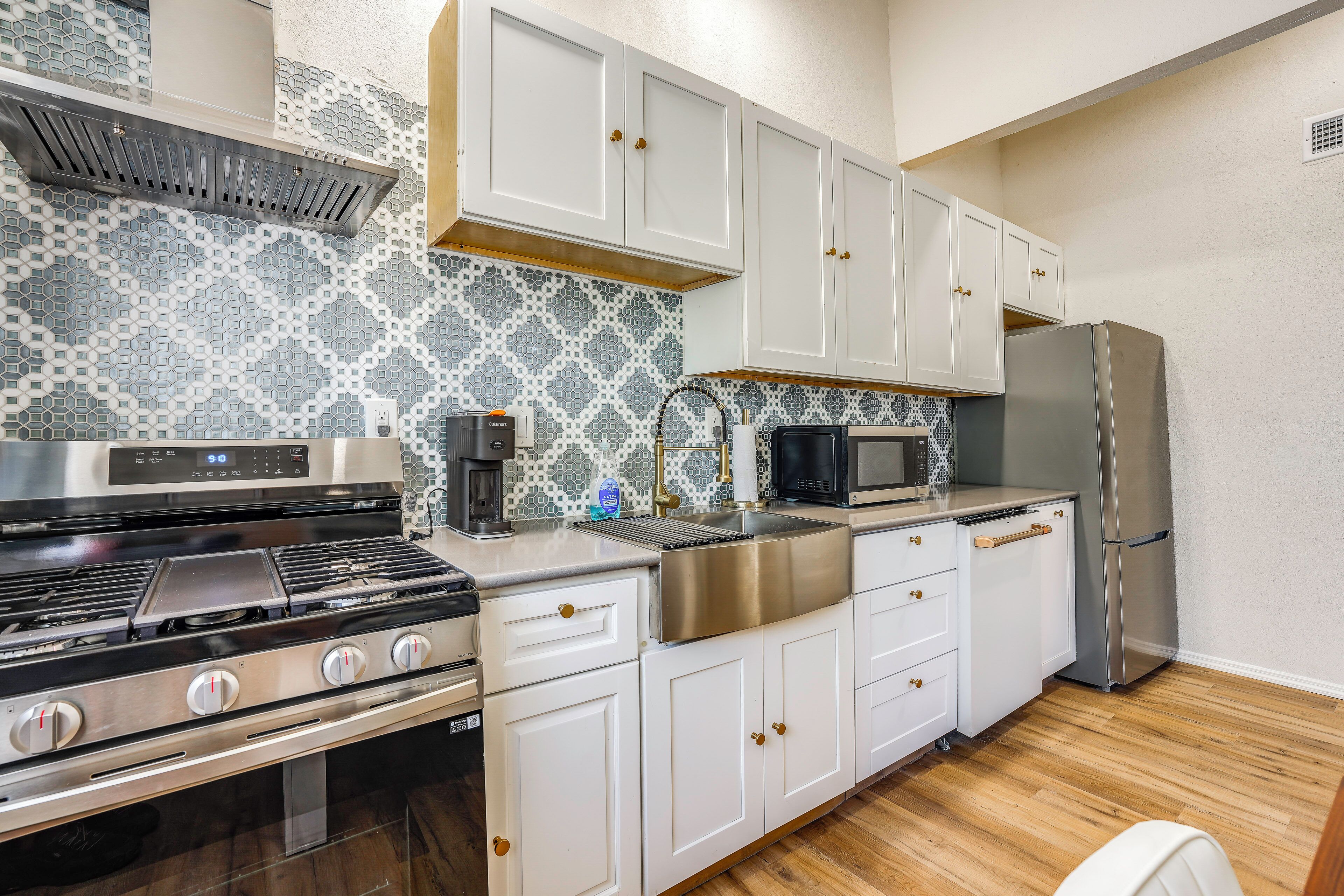 A kitchen with white cabinets, a stainless steel refrigerator, a microwave, and a gas stove.