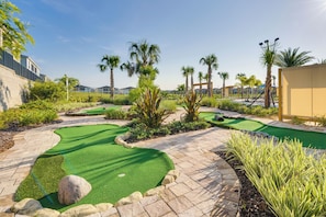 A miniature golf course with green artificial turf, palm trees, and stone pathways. - New Remodeled Championsgate Pool Home 5br/5ba (Davenport)
