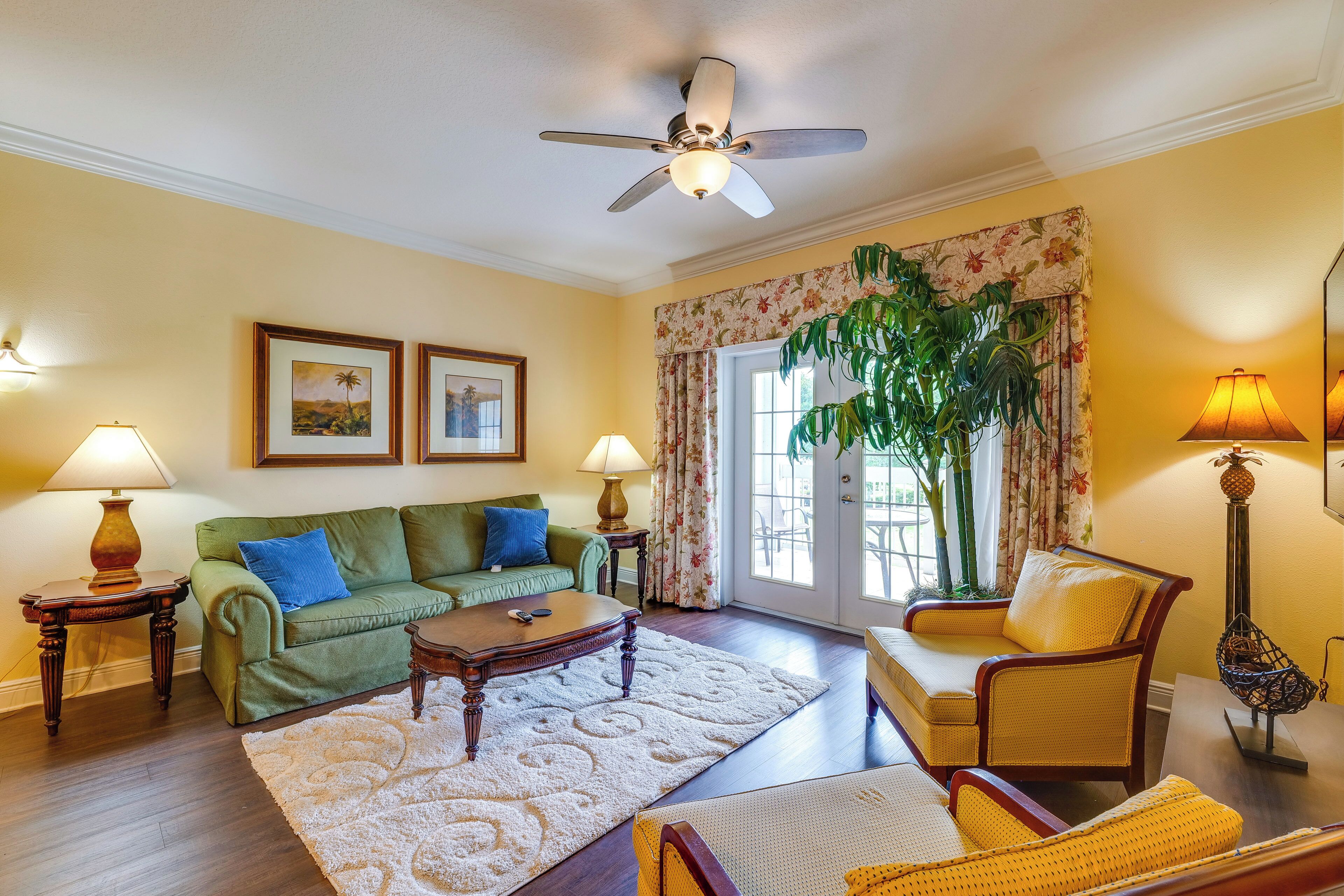 A living room with a green sofa, yellow armchair, wooden coffee table, and a large plant.