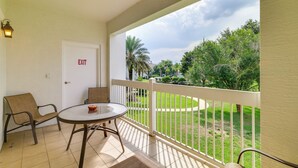A balcony with a table and chairs, an exit door, and a view of a green landscape. - Extended-stay Condo in Reunion Golf Resort (Kissimmee)