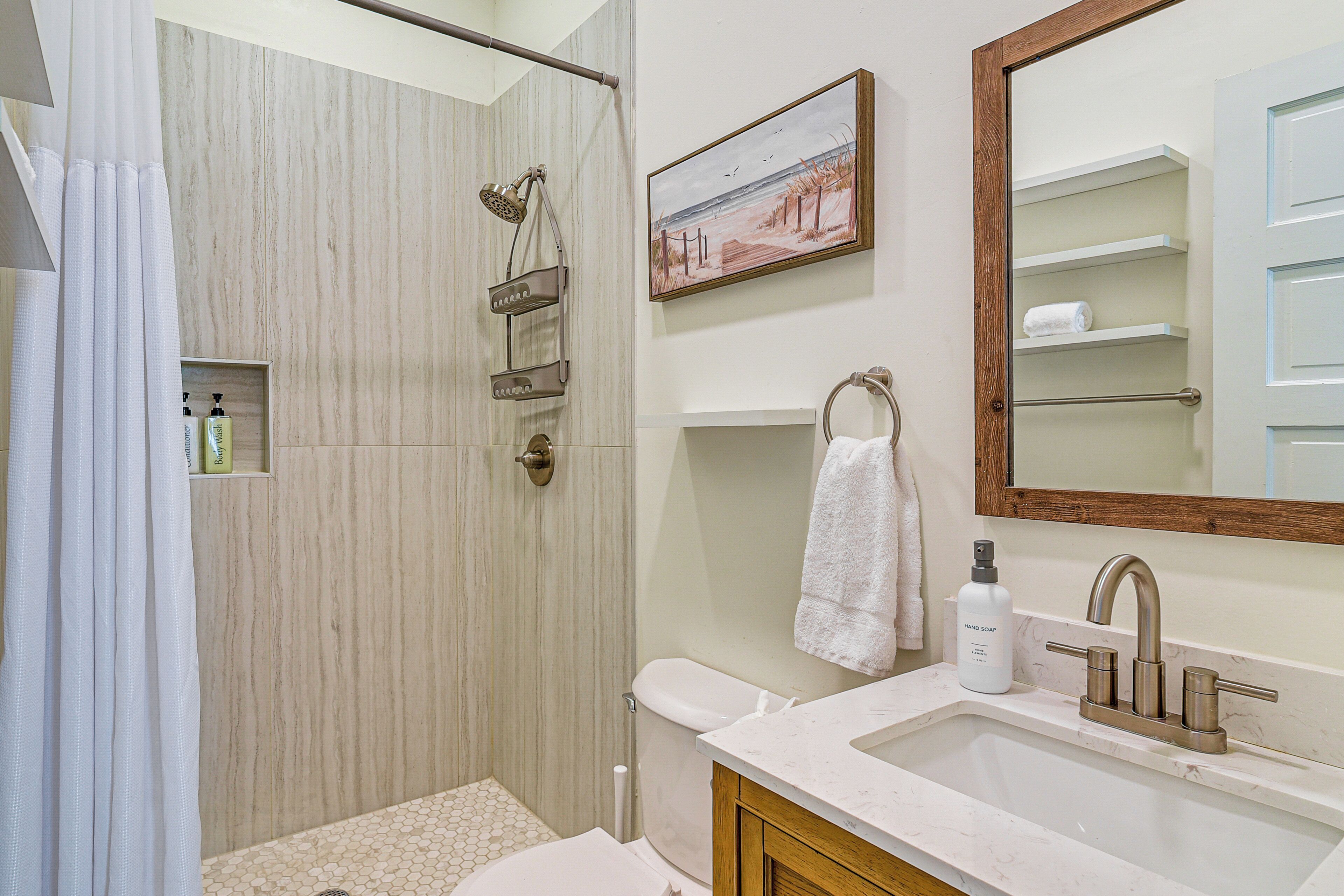 A bathroom with a shower, toilet, sink, and a towel rack.