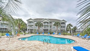 A swimming pool with lounge chairs and palm trees, surrounded by a brick patio. - Condo w/ Pools! 5 Mi to Broadway at the Beach (Myrtle Beach)