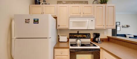 A kitchen with a refrigerator, microwave, stove, and oven.
