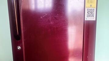 Un réfrigérateur Haier de couleur bordeaux, muni d’un autocollant indiquant les mesures à prendre pour économiser l’énergie.