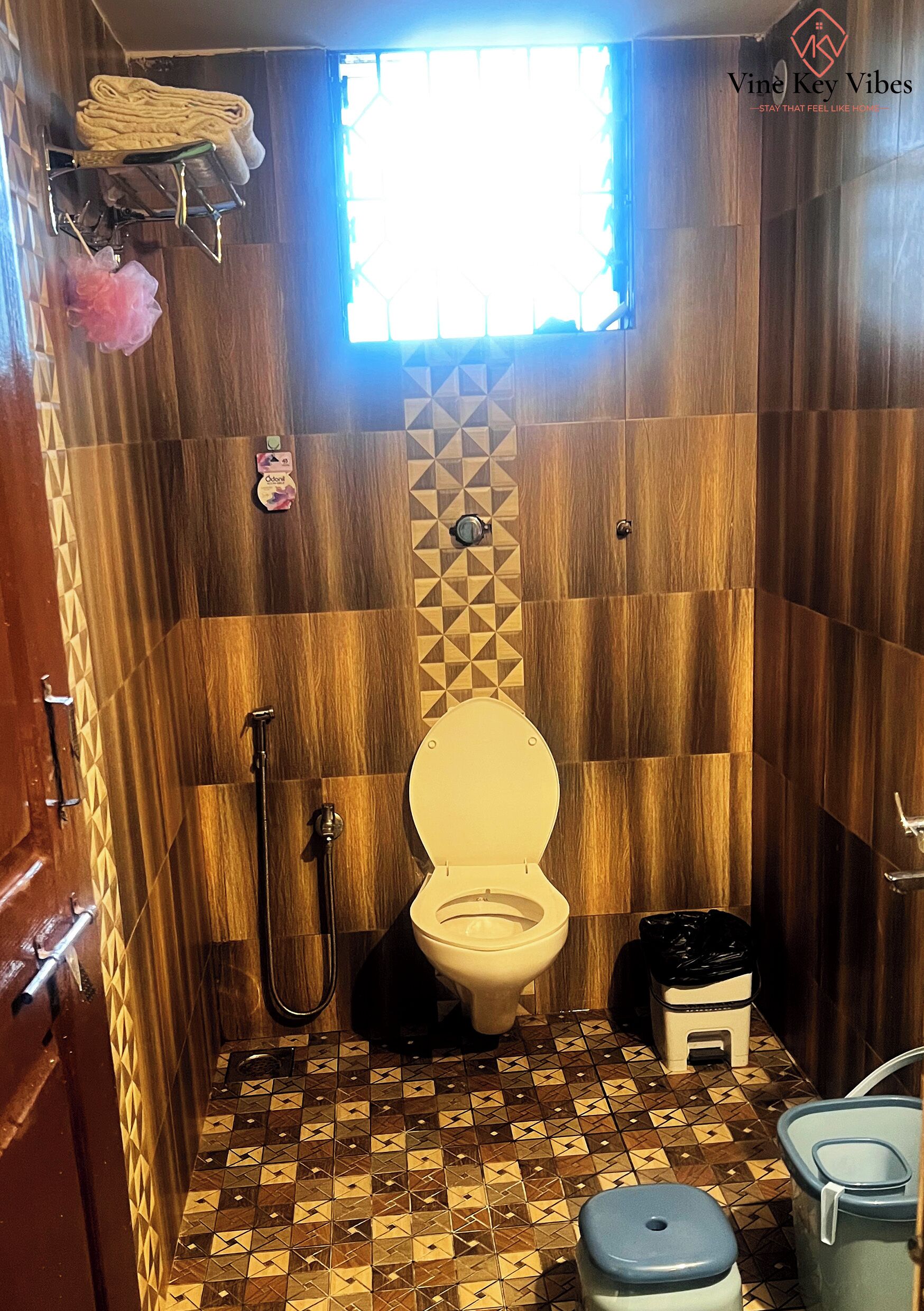 A compact bathroom with a toilet, shower, and a small trash bin.