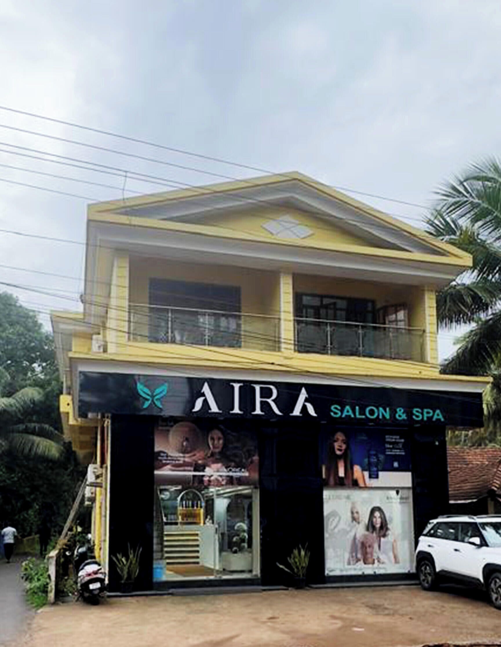 Un bâtiment à deux étages, avec une enseigne indiquant « AIRA SALON & SPA » au rez-de-chaussée.