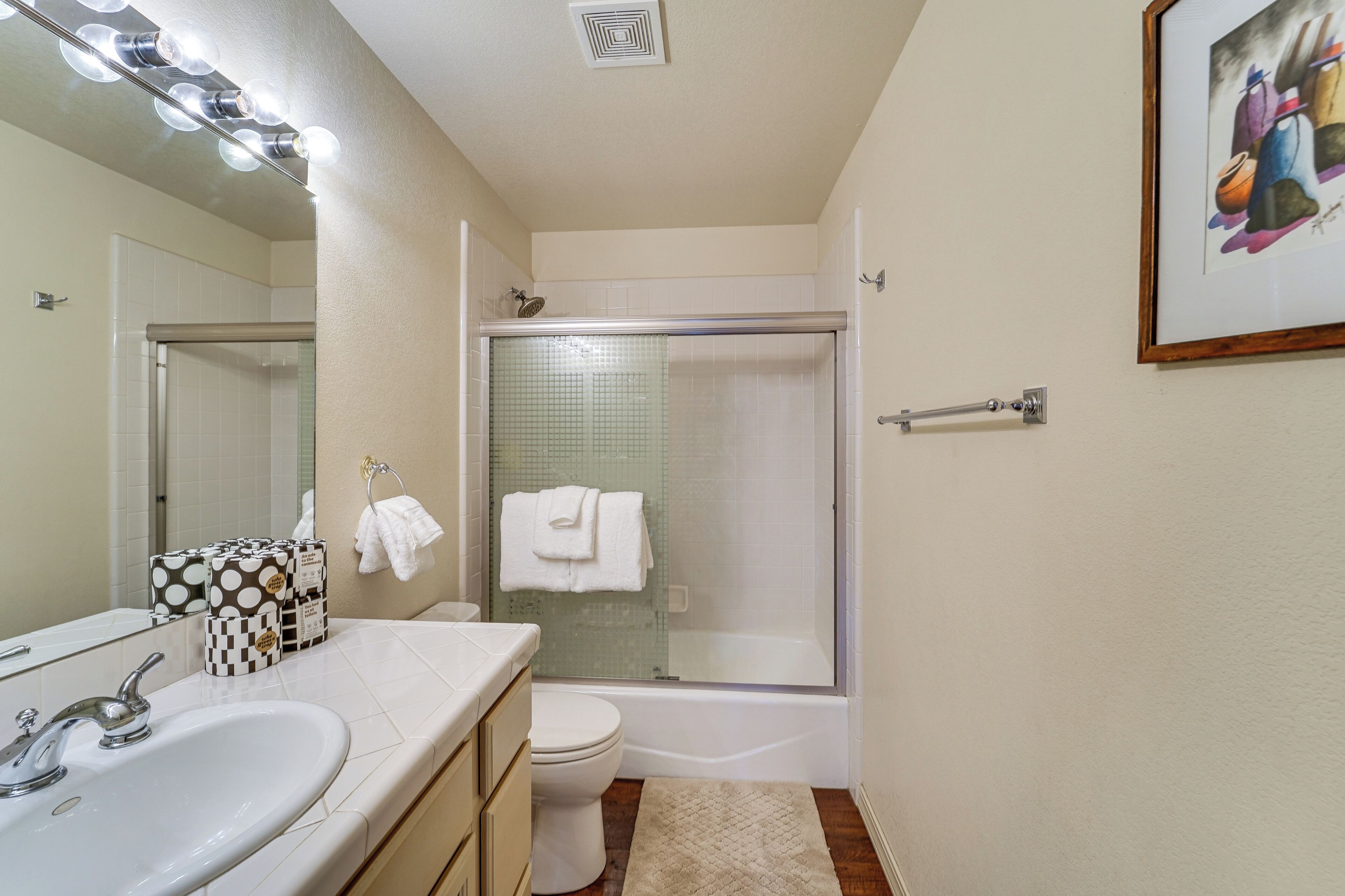 A bathroom with a sink, toilet, shower, and a towel rack.