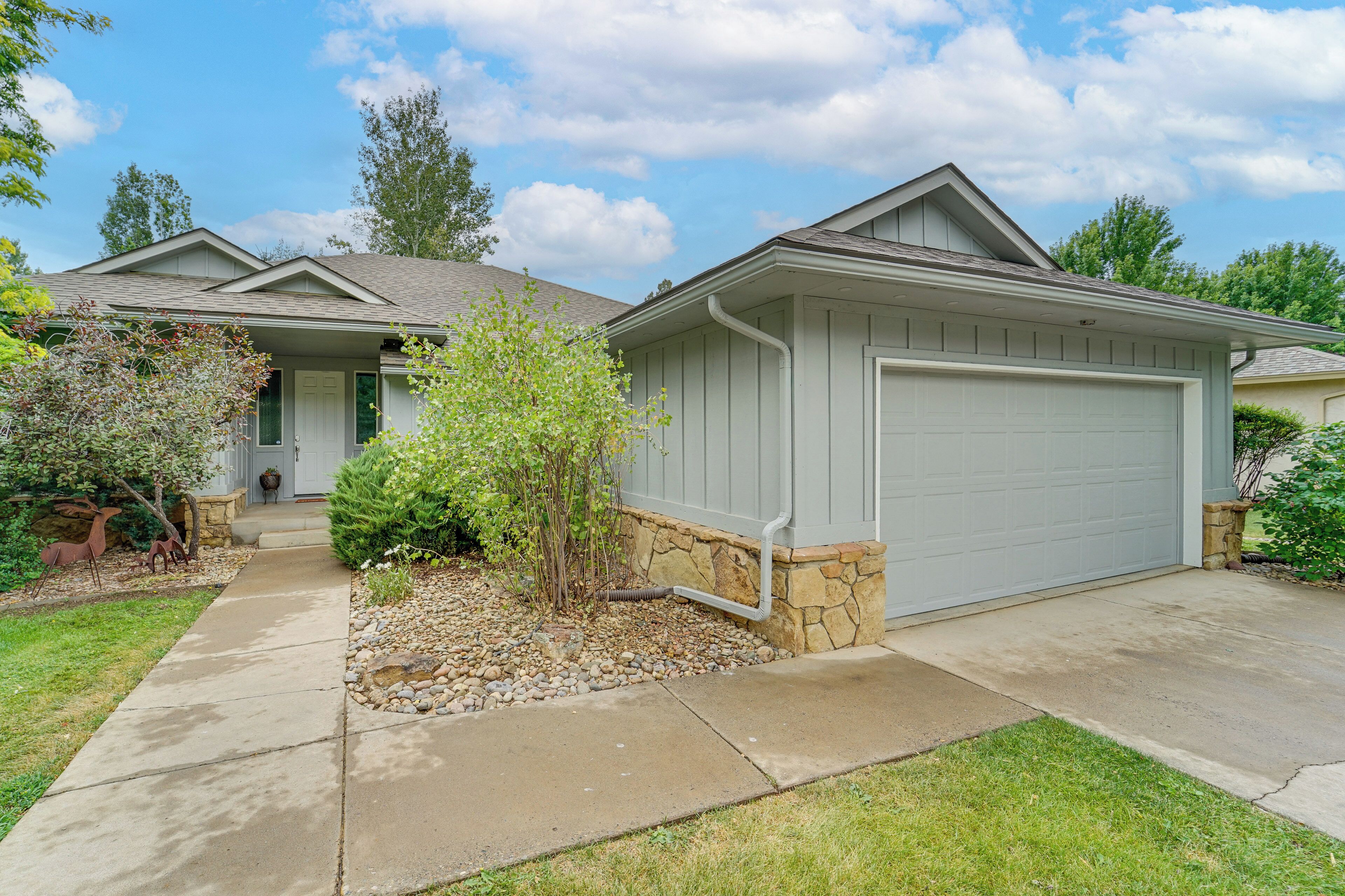 A residential house with a garage, a front porch, and a small garden area with decorative deer statues.
