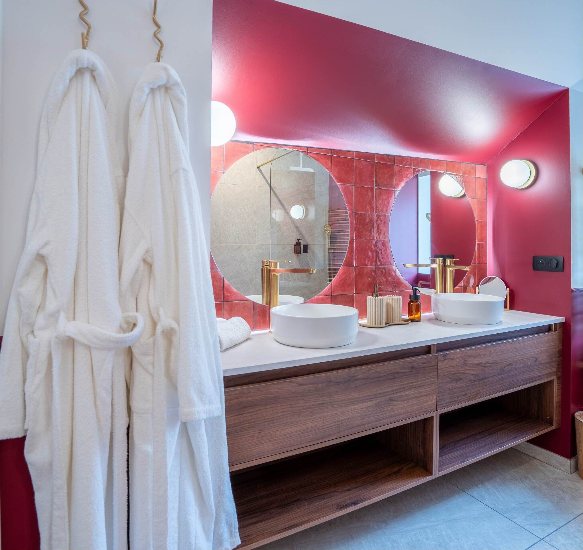 Ein Badezimmer mit Waschtisch, zwei Waschbecken, einem Spiegel und einem Handtuchhalter.