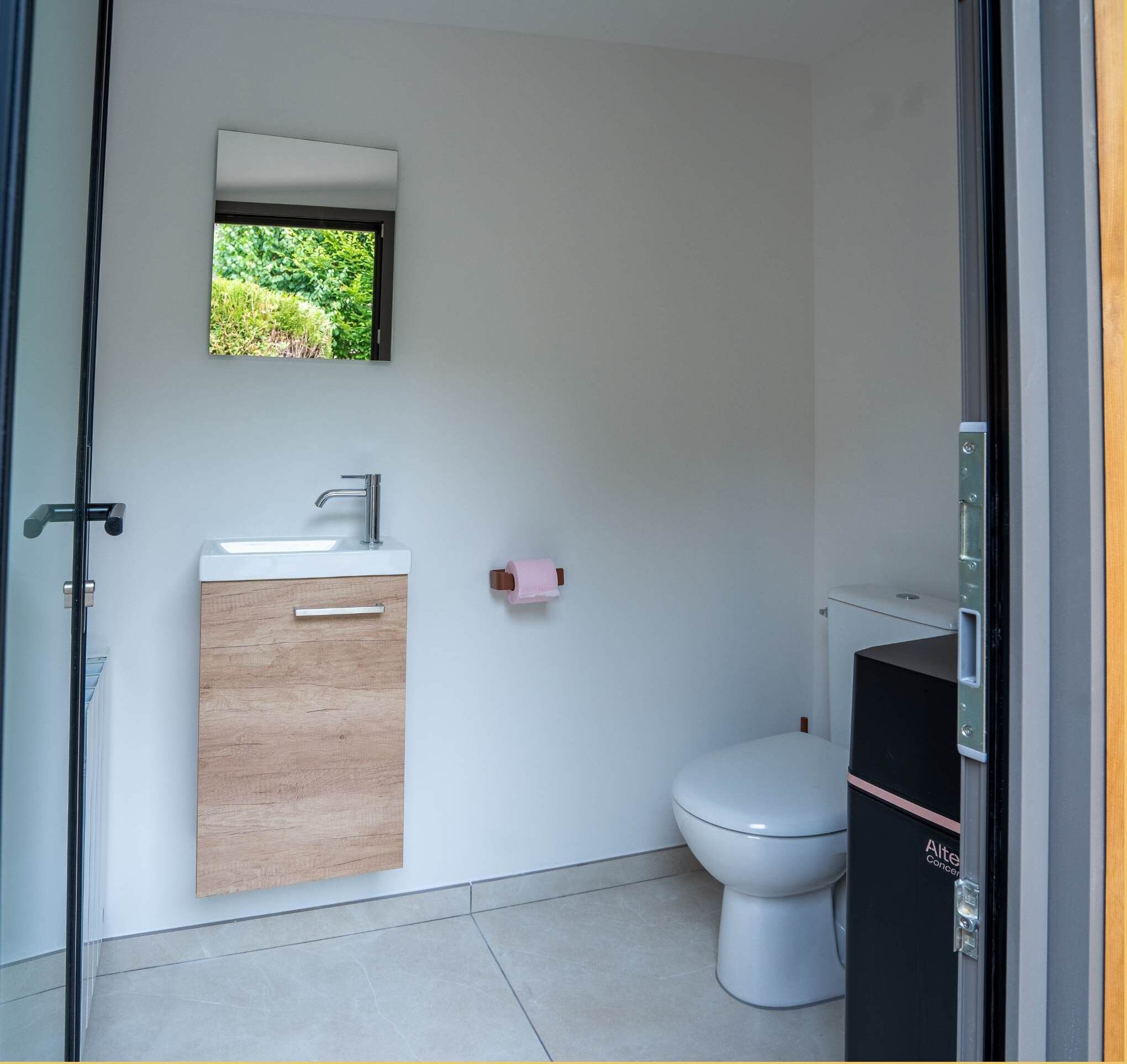 A small bathroom with a toilet, a sink, and a mirror.