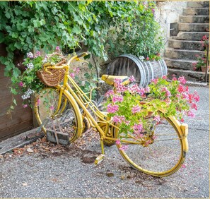 A yellow bicycle with a basket and flowers, parked on a gravel surface. - La Halte du Vigneron I T2 I Vongnes (Vongnes)