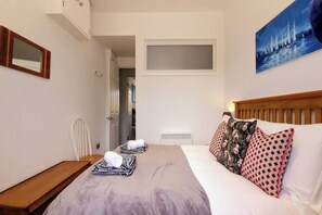Une chambre d’hôtel avec un lit, un bureau, une chaise et un tableau au mur.