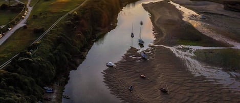 A river with boats, a road, and a sunset.