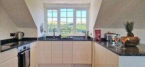 A modern kitchen with a large window, a kettle, a toaster, and a pineapple on the counter.