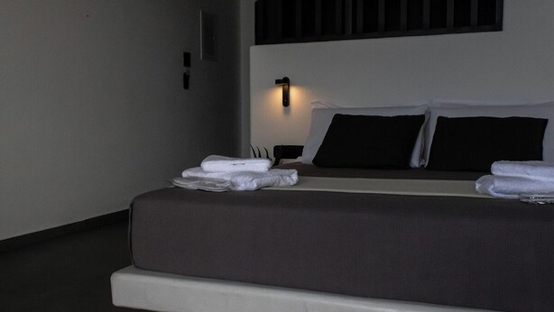 Ein modernes Schlafzimmer mit einem Bett, Nachttischen und einer Wandleuchte.