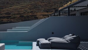 Ein moderner Poolbereich im Freien mit integriertem Sitzbereich und Blick auf eine hügelige Landschaft.