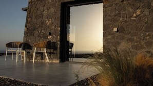 Ein Steinhäuschen mit Terrasse, Stühlen und Aussicht.