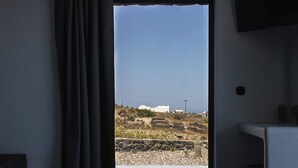 Ein Zimmer mit einer Schiebeglastür, die zu einer felsigen Landschaft mit Gebäuden in der Ferne führt.