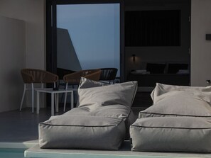 Un espace extérieur moderne, aménagé avec des fauteuils confortables et offrant une vue sur la piscine.