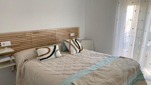 Ein Schlafzimmer mit einem Bett, Kissen, einem Nachttisch und einem Fenster mit Vorhängen.