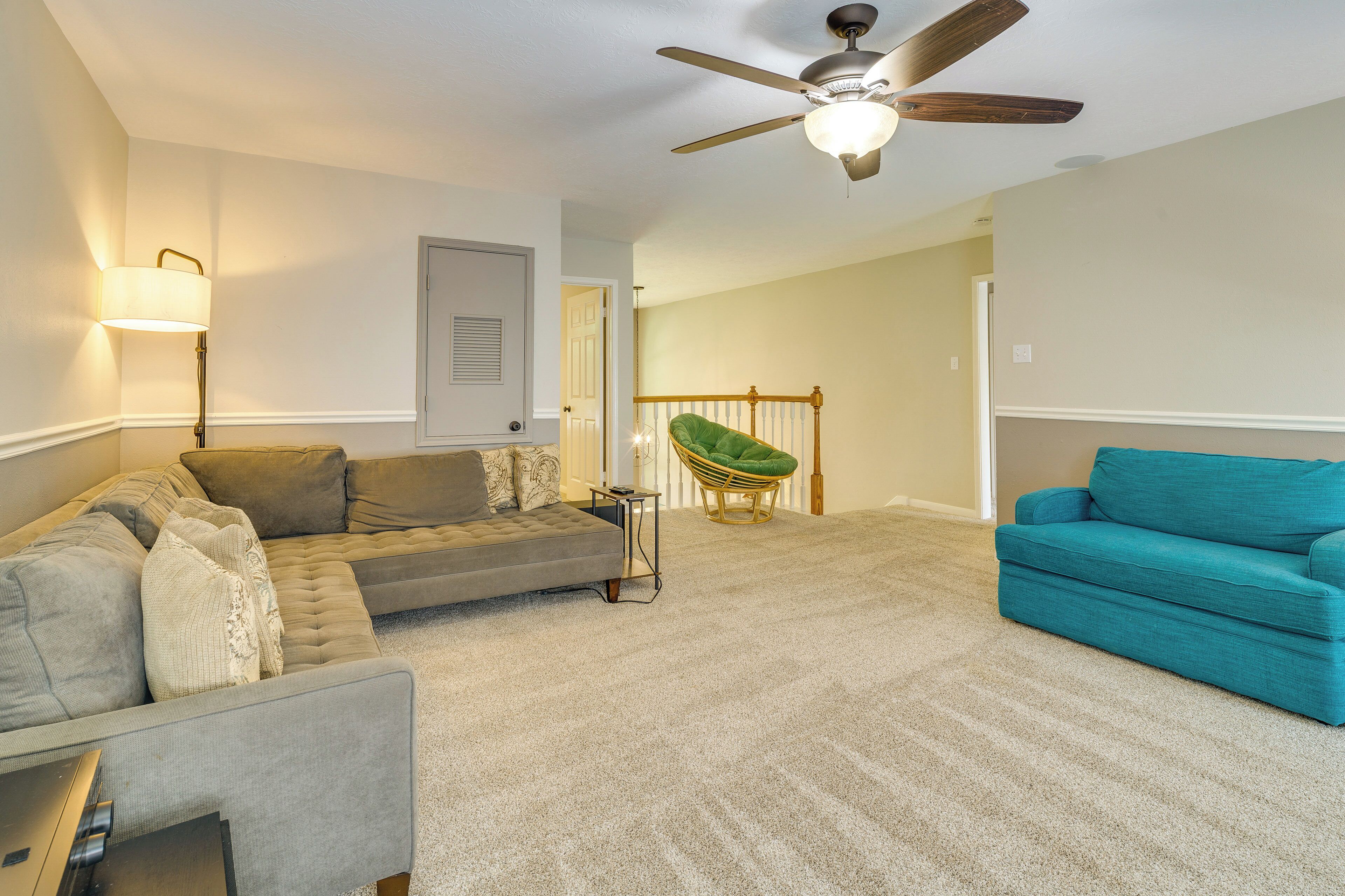 A living room with a sofa, a chair, a lamp, and a ceiling fan.