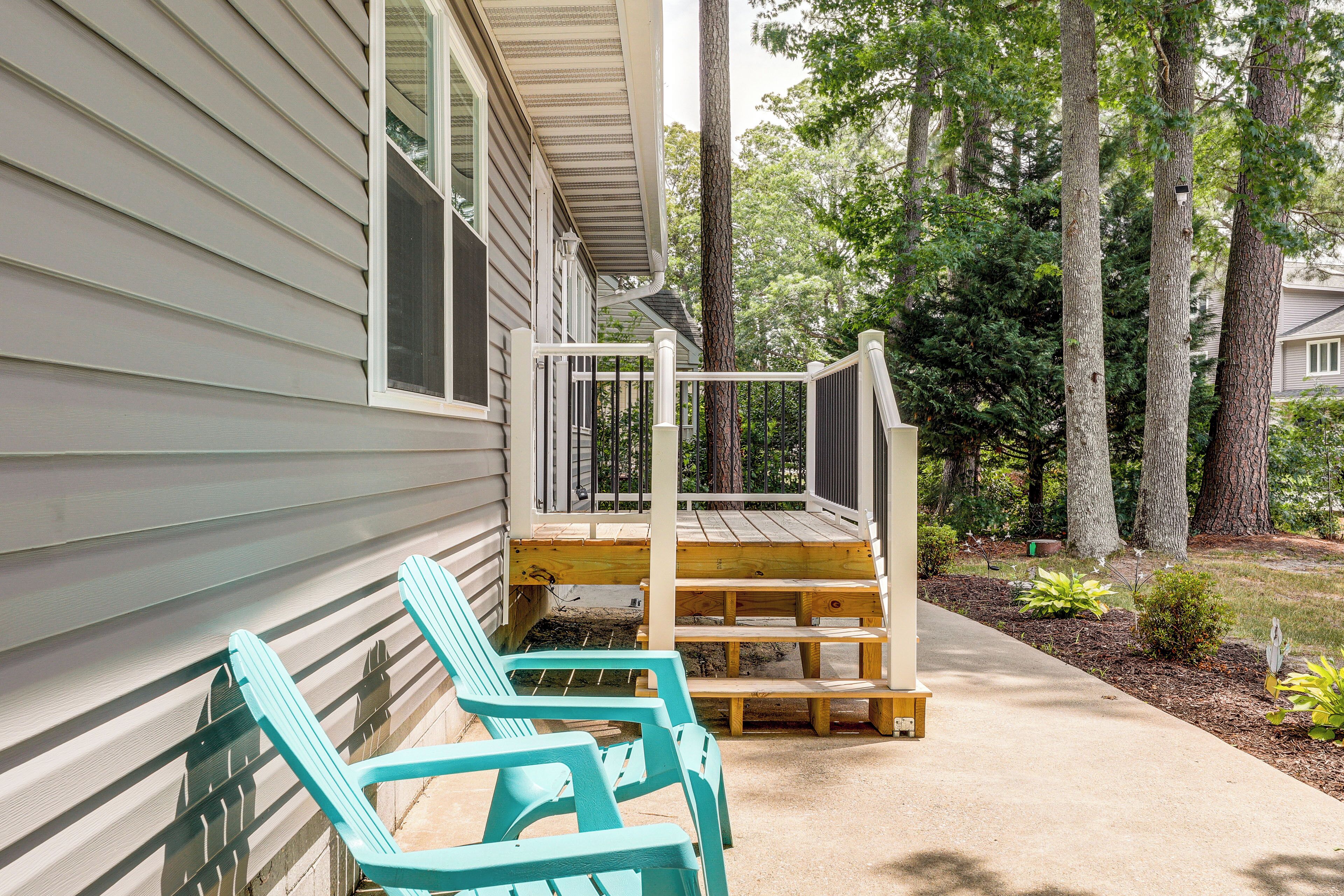 A porch with two turquoise chairs, a wooden deck, and a house with siding.