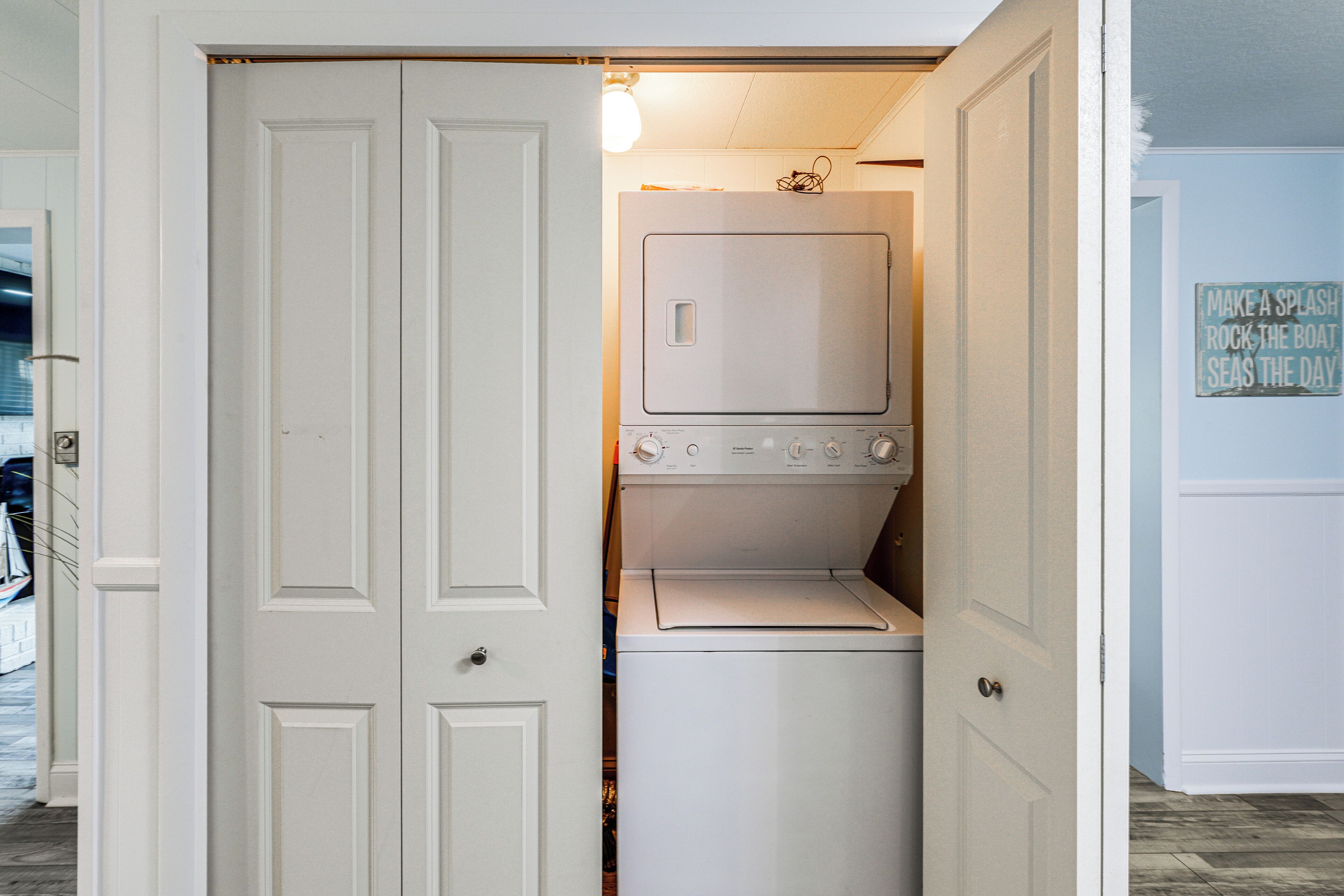 A laundry room with a washer and dryer, a door with a handle, and a wall sign.