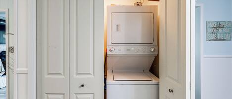 A laundry room with a washer and dryer, a door with a handle, and a wall sign.