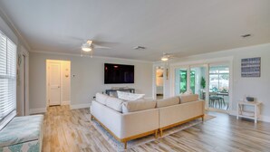 Ein Wohnzimmer mit einer Couch, einem Fernseher und einem Deckenventilator.