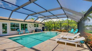 Ein überdachter Pool mit Liegestühlen, einer Grillgelegenheit und Blick ins Freie.