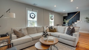 Una sala de estar moderna con un sofá modular, una mesa de centro y una escalera.
