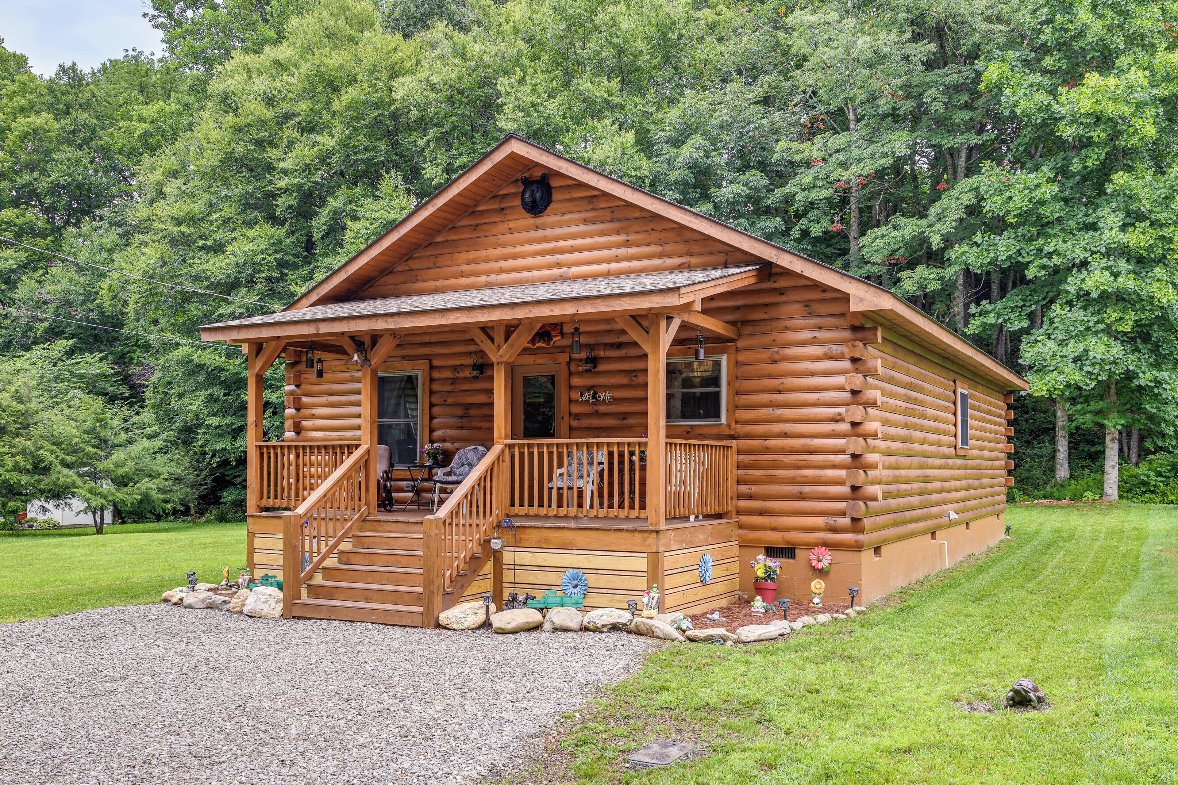 A log cabin with a porch, a staircase, and a small deck area.