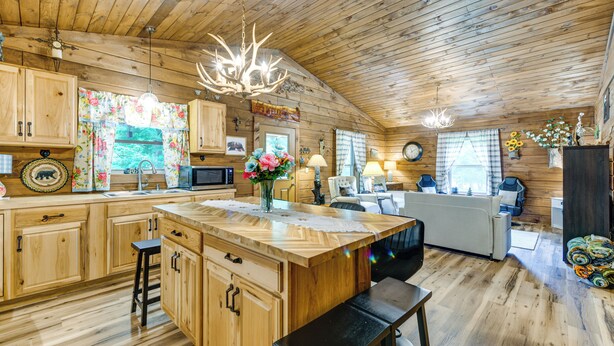 A cabin interior with wooden walls, a central island with stools, a kitchen area, and a cozy seating space. - Great for Elk Viewing! Creekside Maggie Valley Gem (Maggie Valley)