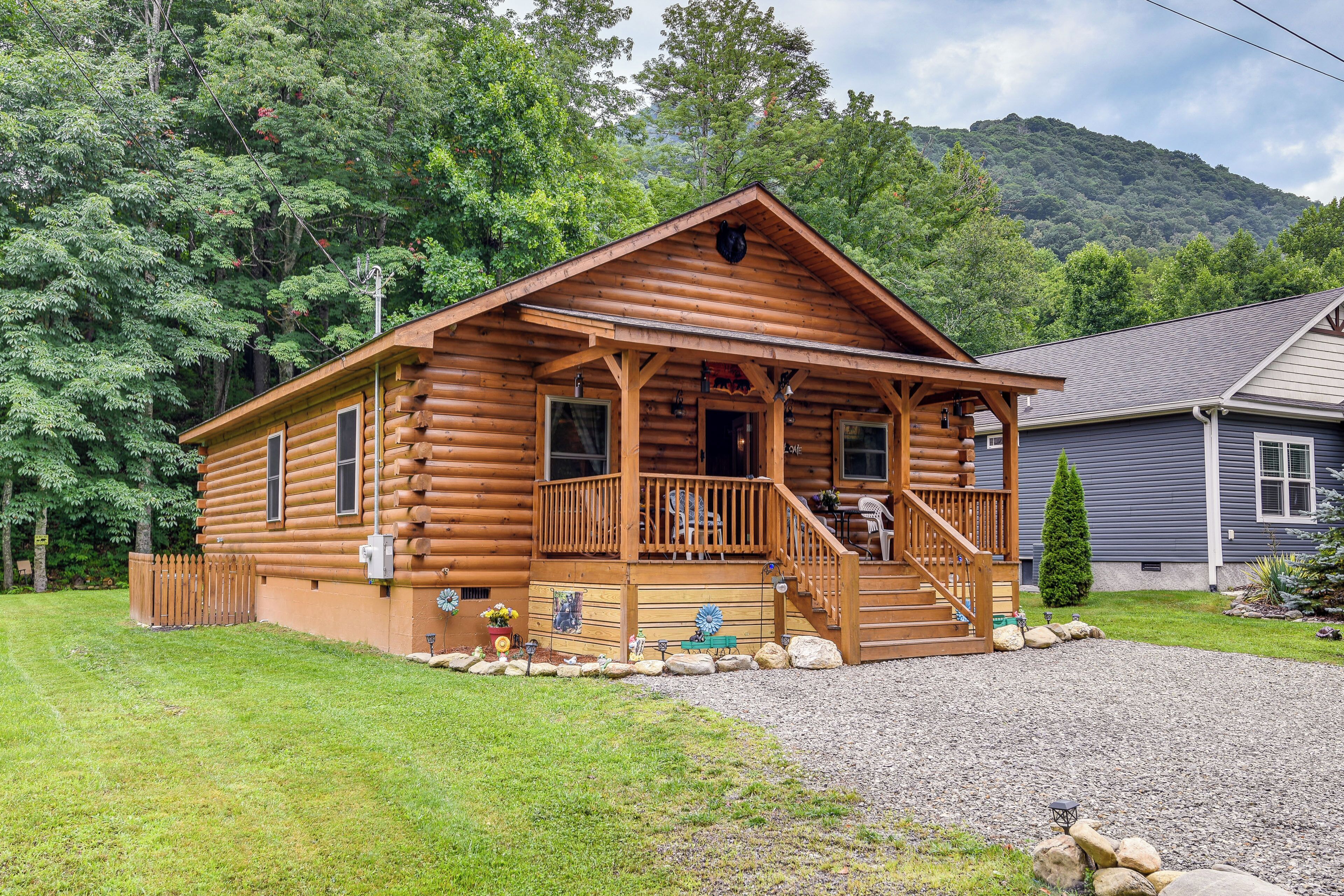 A log cabin with a porch, a staircase, and a small deck.