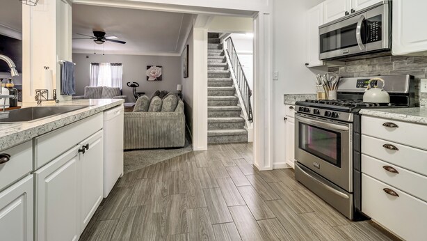 A modern kitchen with white cabinetry, stainless steel appliances, and a herringbone-patterned floor. - 4 Mi to Utoledo! Cozy Family Home (Toledo)