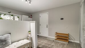 A clean, modern hallway with a bench, a small table with a plant, and a wooden bench by the door. - 4 Mi to Utoledo! Cozy Family Home (Toledo)