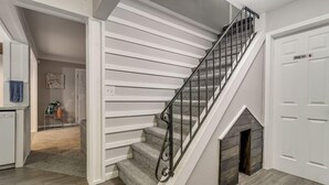 Uma escadaria com corrimão de metal, uma lareira e uma porta com a inscrição 'Master Suite'.