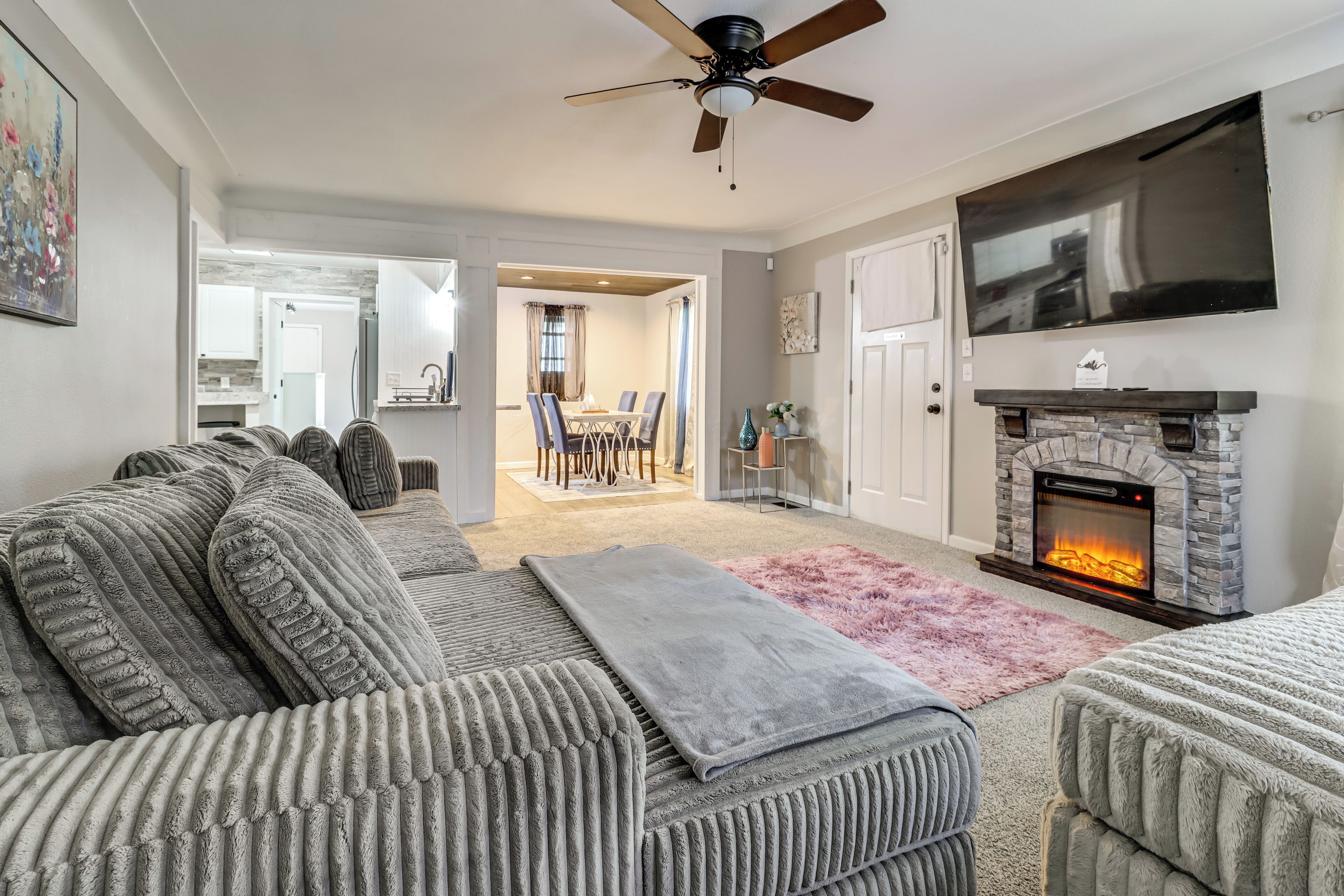 A living room with a fireplace, a ceiling fan, and a TV mounted on the wall.